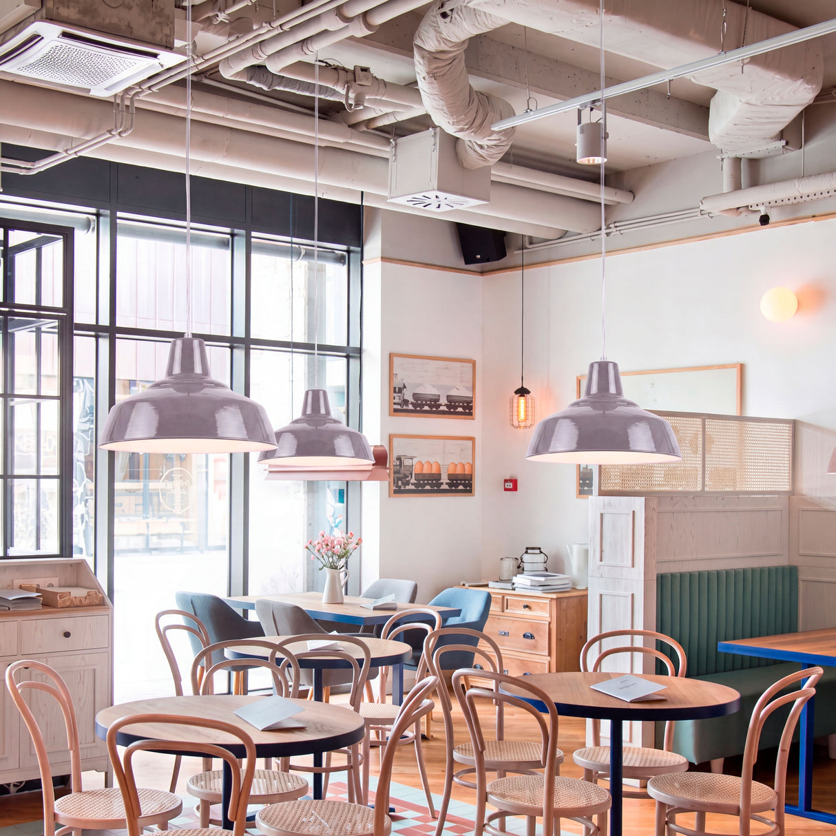 Tres lámparas suspendidas aportando alta eficiencia lumínica en una cafetería de arquitectura contemporánea.