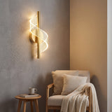 Lampara Helix Gold proyectando luz calida sobre un sillon de lectura, creando una atmosfera acogedora.