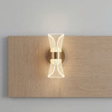 Lampara de pared Galaxy Gold instalada verticalmente sobre un revestimiento de madera clara minimalista.