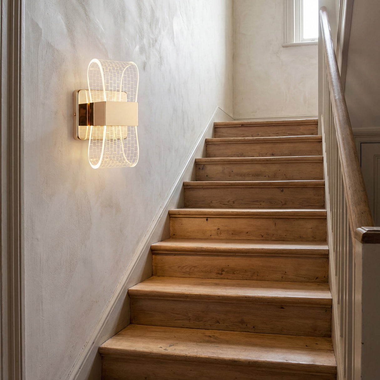 Aplique LED Cubic Gold instalado en la pared de una escalera interior para guiar el paso con elegancia.
