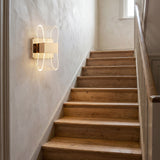Aplique LED Cubic Gold instalado en la pared de una escalera interior para guiar el paso con elegancia.