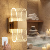 Aplique de pared Cubic Gold con diseño de mosaico iluminando un área de relajación con tina, toallas y piedras zen.