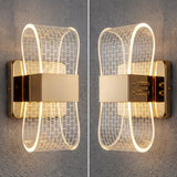 Dos luminarias Cubic Gold instaladas simétricamente en una pared gris, resaltando su diseño de bucles rectangulares.