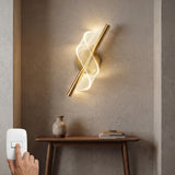 Lampara de pared Helix Gold vertical en un espacio de descanso junto a un cuadro decorativo.