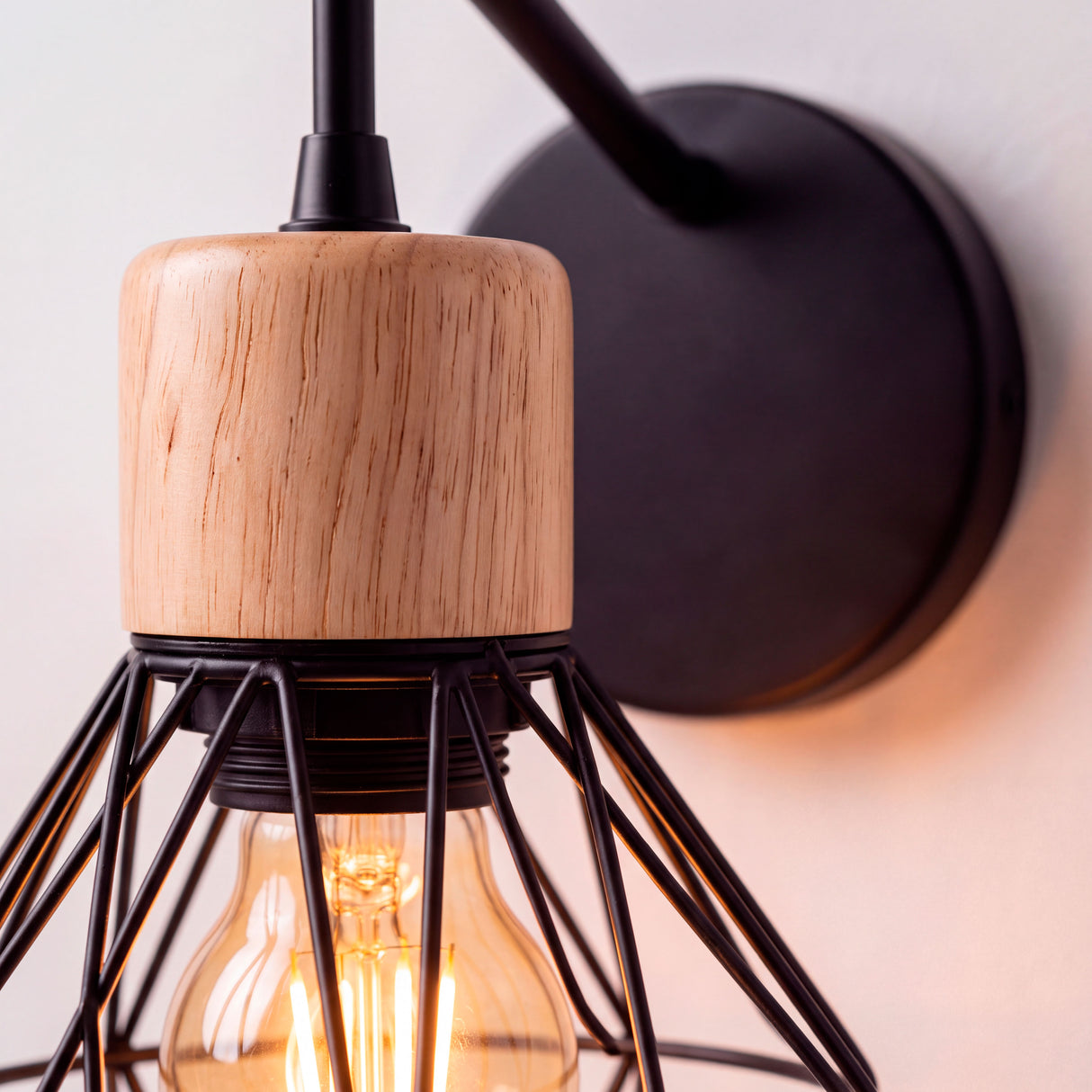 Primer plano de casquillo decorativo de madera natural y jaula de alambre negro mate con diseño minimalista.