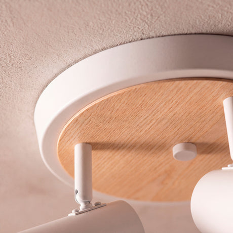 Detalle en primer plano del florón metálico en blanco mate combinado con placa de madera natural.