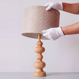 Detalle del montaje de la pantalla textil beige sobre la estructura de madera torneada.