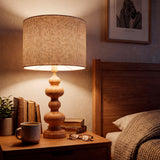 Lámpara de madera en mesilla de noche con accesorios, creando atmósfera de descanso.