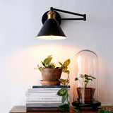 Aplique de pared con brazo extensible en negro y dorado mate para proyectos de iluminación técnica.