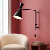 Aplique de pared articulable IRIS negro mate sobre sillón de lectura bouclé