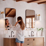 Aplique blanco con dorado iluminando baño donde se lavan madre e hijo
