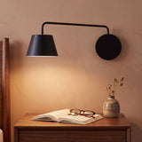 Aplique de pared OSLO negro con brazo giratorio iluminando un velador con libro