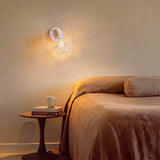 Aplique de pared blanco iluminando la cabecera de un dormitorio