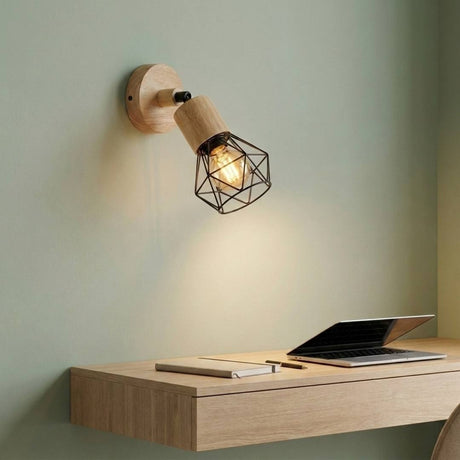 Aplique de pared GRETA de madera con jaula negra encendido sobre un escritorio de madera