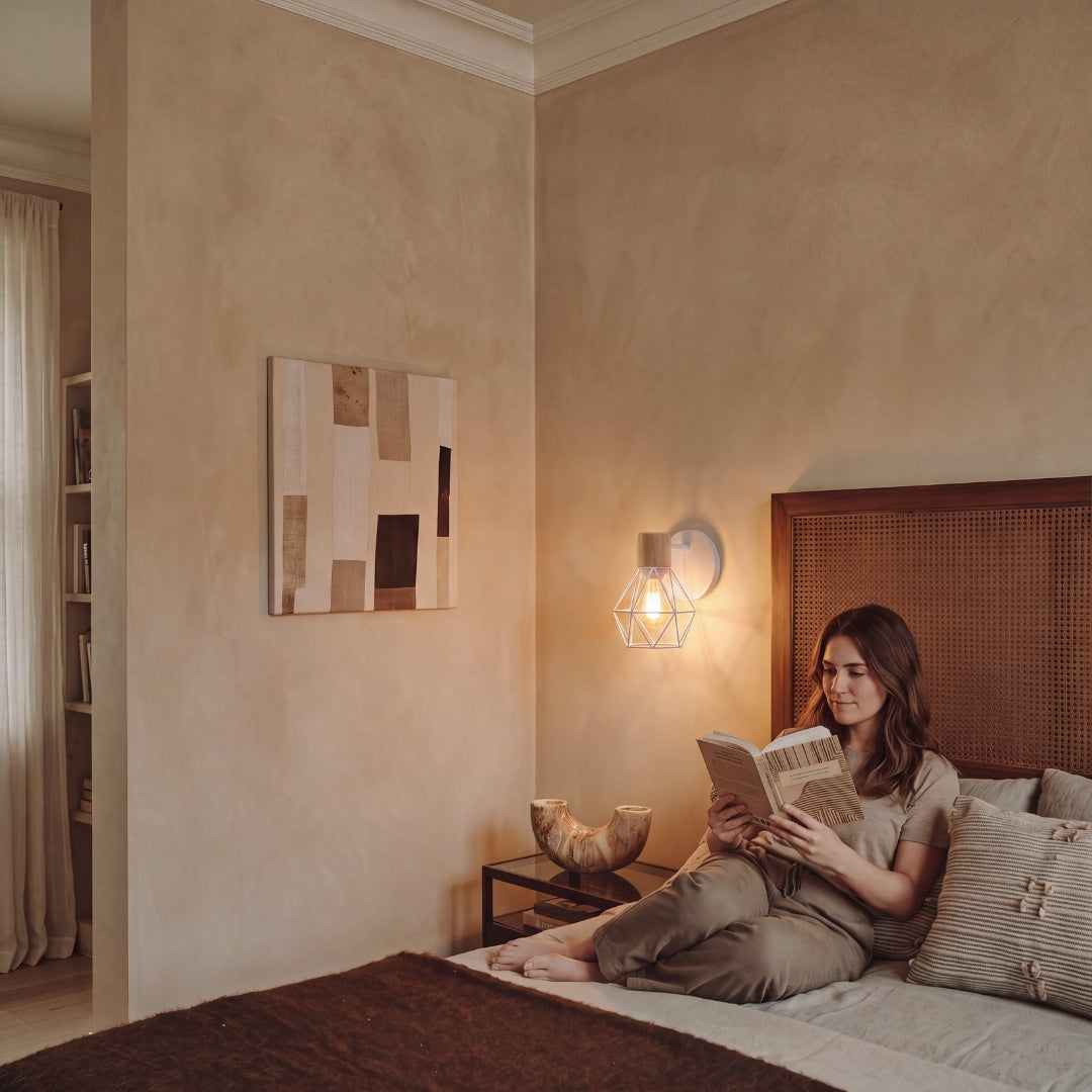 Persona leyendo en cama con aplique de pared de luz cálida