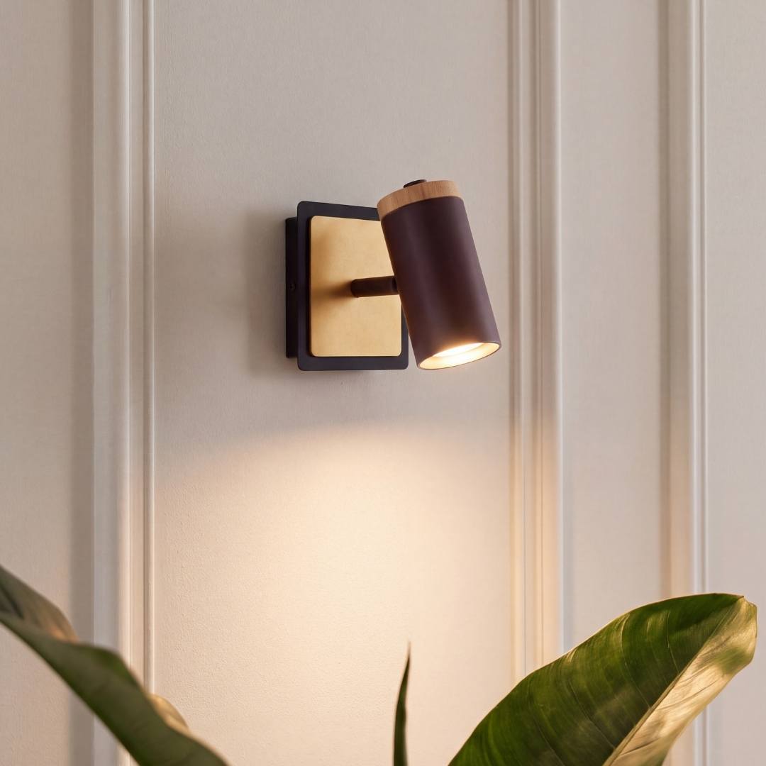 Aplique de pared encendido proyectando luz cálida junto a una planta