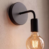Aplique negro con foco vintage de filamento encendido en la pared