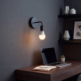 Aplique de pared negro con foco vintage encendido sobre el escritorio