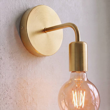 Aplique dorado con foco vintage de filamento encendido en la pared