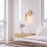Aplique de pared dorado con foco vintage encendido junto a la cama