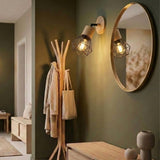 Aplique de pared orientable de madera iluminando un recibidor con perchero y espejo
