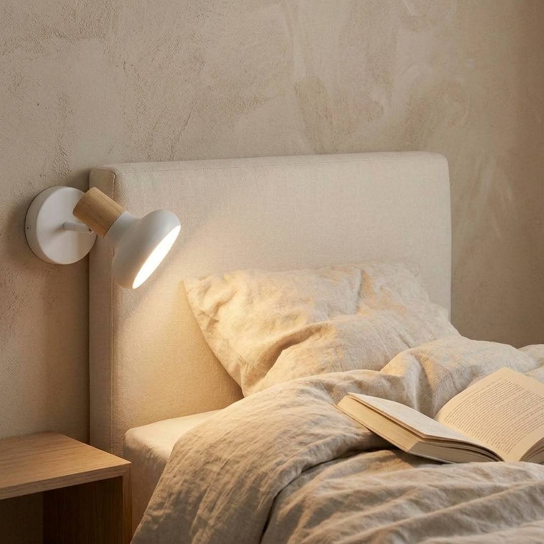 Aplique orientable blanco en la cabecera de un dormitorio