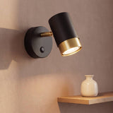 Aplique de pared negro con anillo dorado y cabezal girable encendido