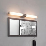 Lámpara de pared cilíndrica Nery Silver de 12W sobre espejo con marco negro.