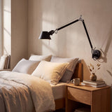 Aplique de lectura encendido con luz cálida sobre cama en tonos beige