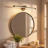 Integración decorativa de luminaria lineal negra sobre un espejo circular en un baño de concepto spa y relajante.