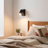 Luminaria de pared negra mate utilizada como luz de lectura sobre la cabecera en dormitorio.