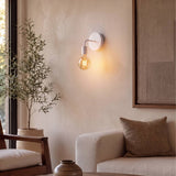 Aplique de pared encendido con luz cálida junto al sofá