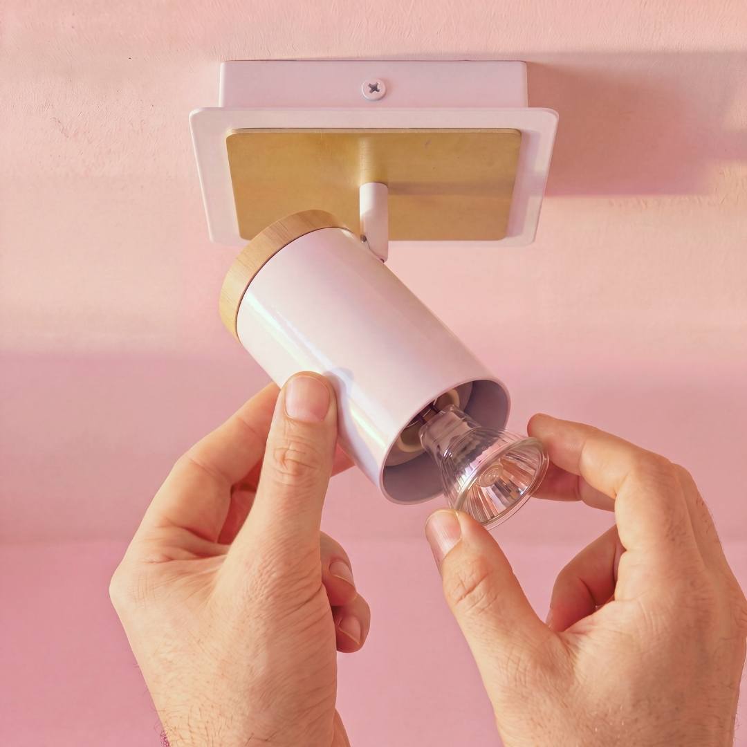 Mano ajustando el cabezal direccionable del spot de pared blanco