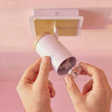 Mano ajustando el cabezal direccionable del spot de pared blanco