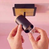 Mano ajustando el cabezal direccionable del spot de pared negro