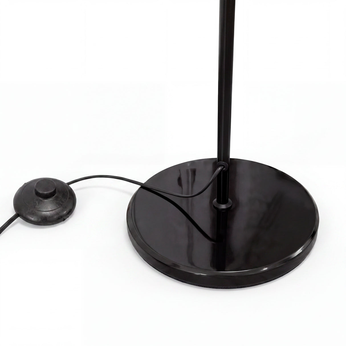 Primer plano de base circular plana en acabado negro mate con salida de cable de alimentación.