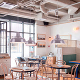 Tres lámparas suspendidas aportando alta eficiencia lumínica en una cafetería de arquitectura contemporánea.