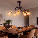 Plafón de brazos distribuidos proyectando una luz cálida sobre mesa de comedor en ambiente de concepto abierto.