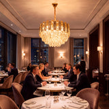 Candelabro de cristal suspendido aportando luz cálida de acento en un comedor comercial de alta gama.