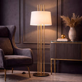 Foco decorativo vertical con estructura tubular dorada proyectando un flujo luminoso acogedor en un rincón de lectura.