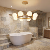 Iluminacion para baño tipo spa con la lampara Collier Gold suspendida sobre una tina de baño blanca.