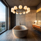 Iluminacion para baño de diseño spa con la lampara Collier Gold suspendida sobre una tina de piedra.
