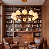 Lampara circular Collier Gold instalada en una biblioteca privada con sillones de cuero y luz calida.