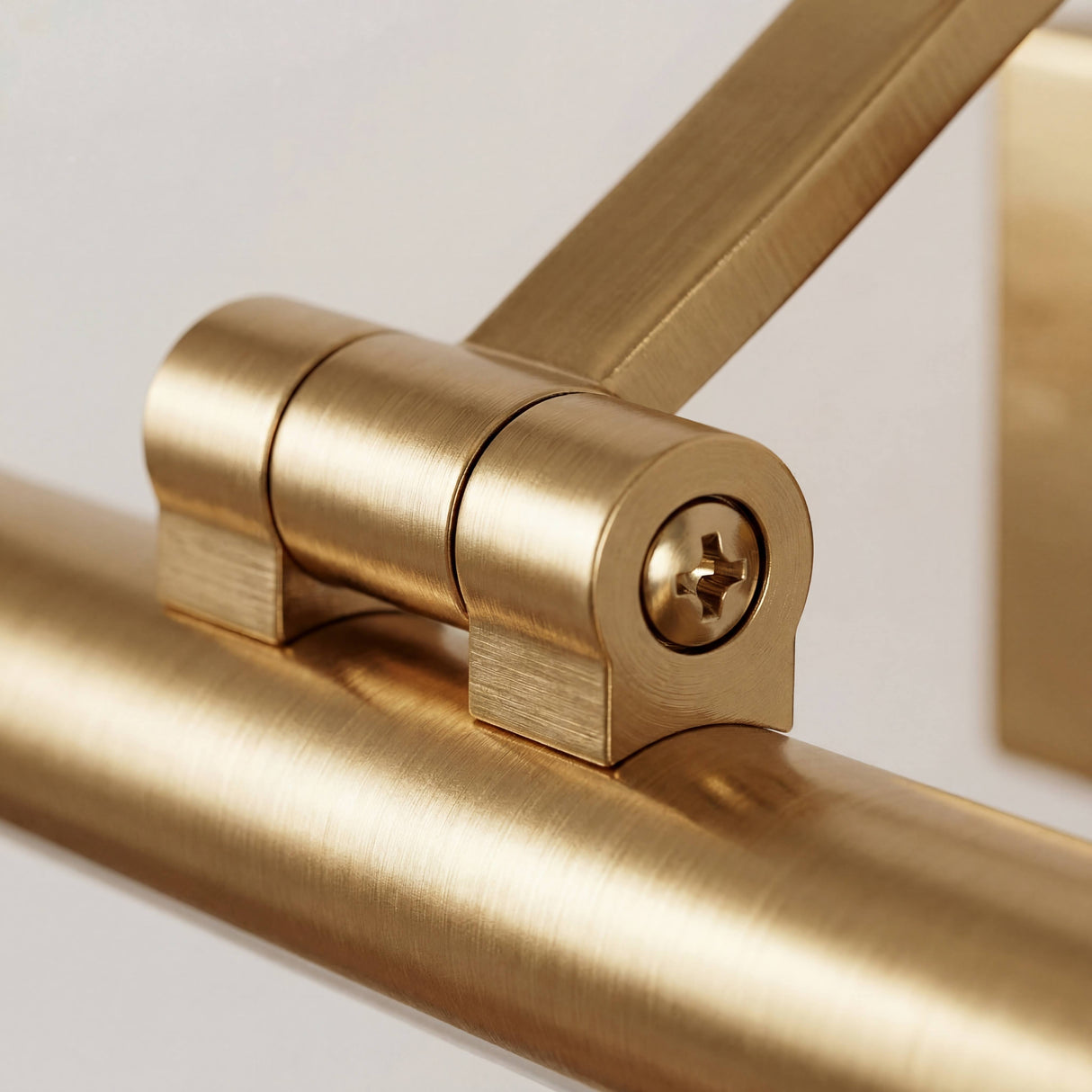 Detalle técnico de la rótula dorada con tornillo de fijación para regular la inclinación del haz de luz.