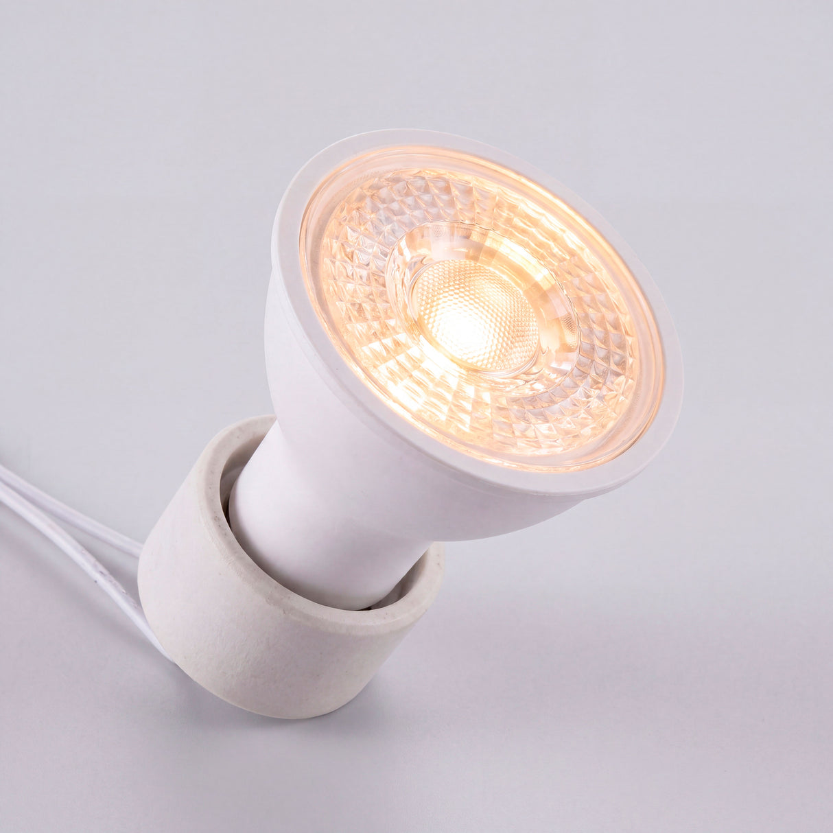 Conector cerámico con lámpara dicroica proyectando un haz de luz neutra y homogénea libre de parpadeo.
