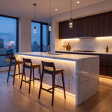 Cocina abierta con alacenas y barra iluminadas con cinta LED cálida