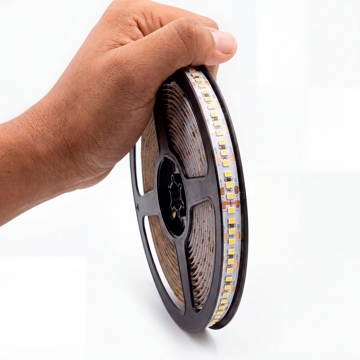 Mano sujetando bobina de tira flexible para proyectos de diseño minimalista e iluminación arquitectónica.