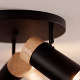 Detalle técnico de rótula giratoria en foco de sobreponer negro con acabados premium en madera natural.