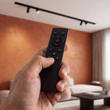 Control remoto smart para riel magnético 48V en mano con spots encendidos de fondo