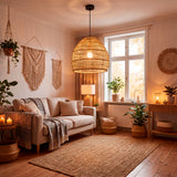 Lámpara de fibras vegetales en salón con luz natural, plantas y textiles de lino.